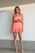 Front view of model wearing coral pleated two-piece set
