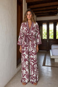 Front view of woman wearing burgundy floral wrap jumpsuit