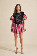 Front view of model wearing black graphic print puff sleeve drop waist mini dress