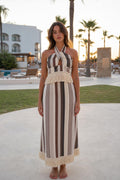 Front view of model wearing beige stripe halter fringe maxi dress outdoors