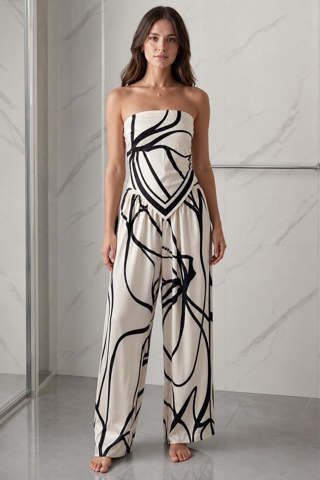 Front view of woman wearing beige and black abstract print strapless jumpsuit