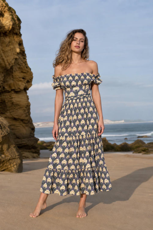 Front view of woman wearing blue floral off-the-shoulder midi dress on a beach