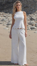 Front view of woman wearing white embroidered two-piece set on a beach