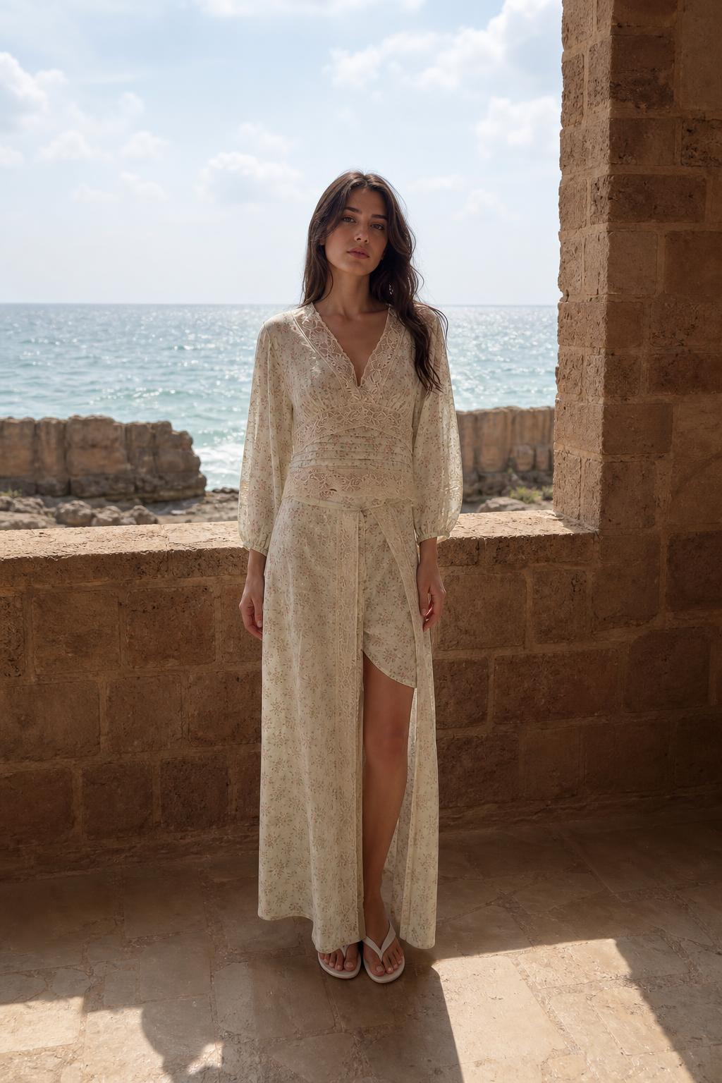 Front view of woman wearing cream floral lace trim maxi dress by the sea