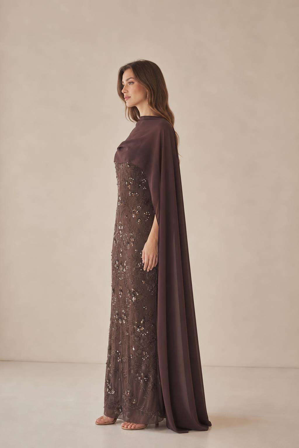 Side profile of model in brown cape evening gown