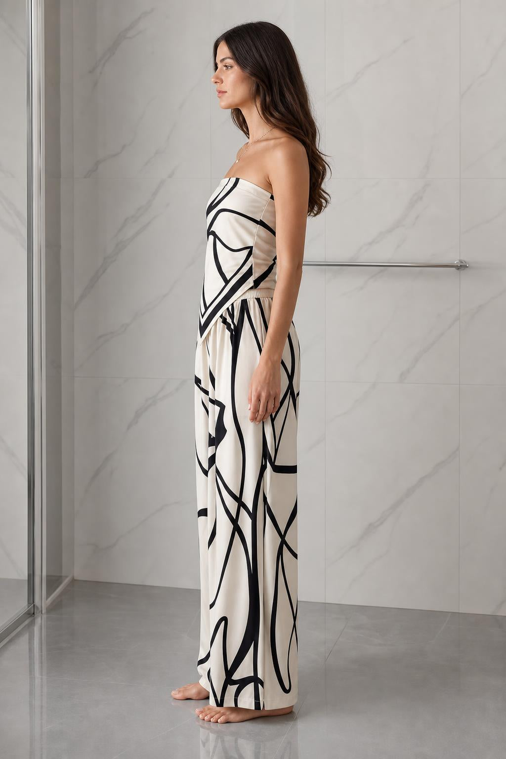 Side profile view of woman wearing beige and black abstract print strapless jumpsuit