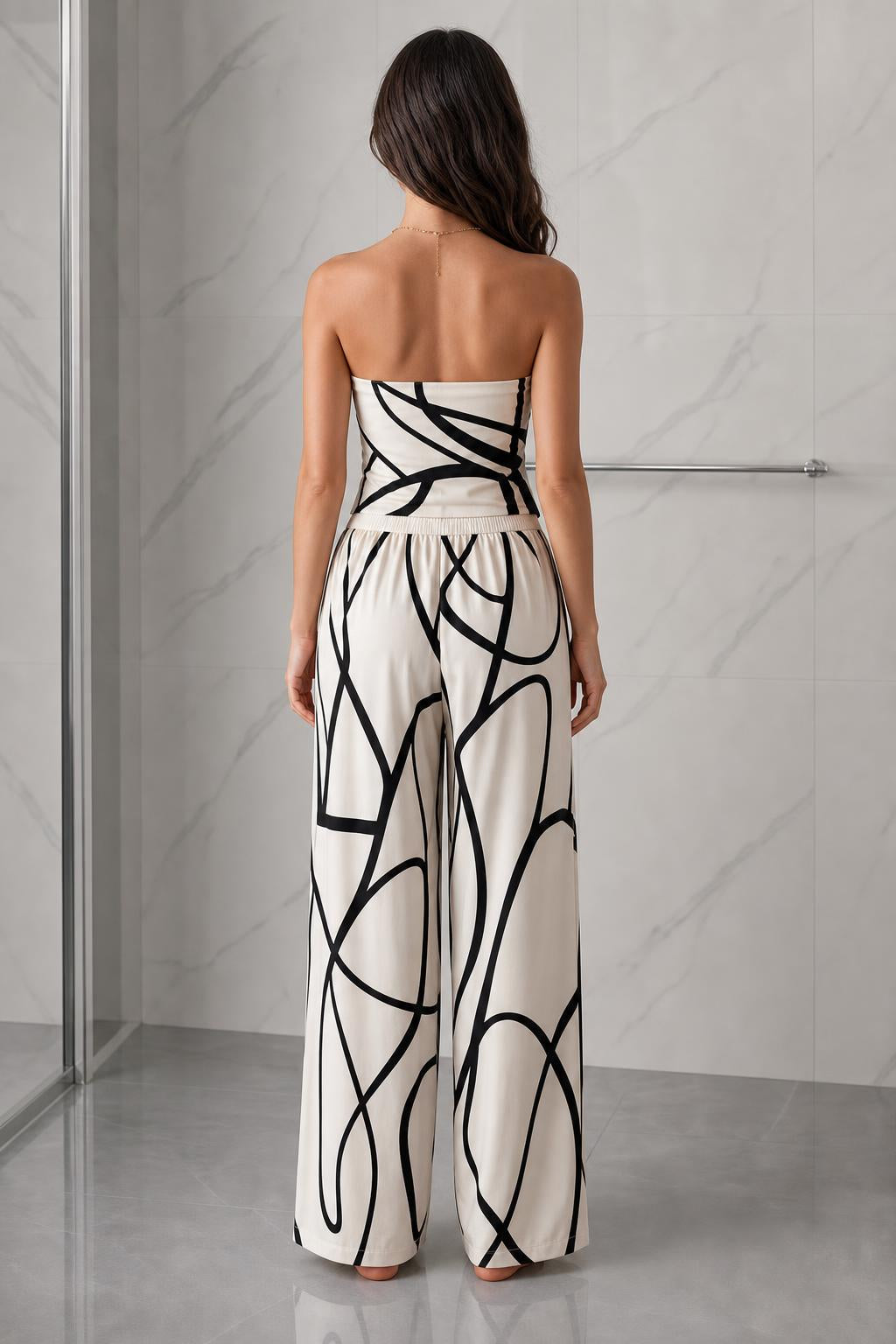 Back view of woman wearing beige and black abstract print strapless jumpsuit