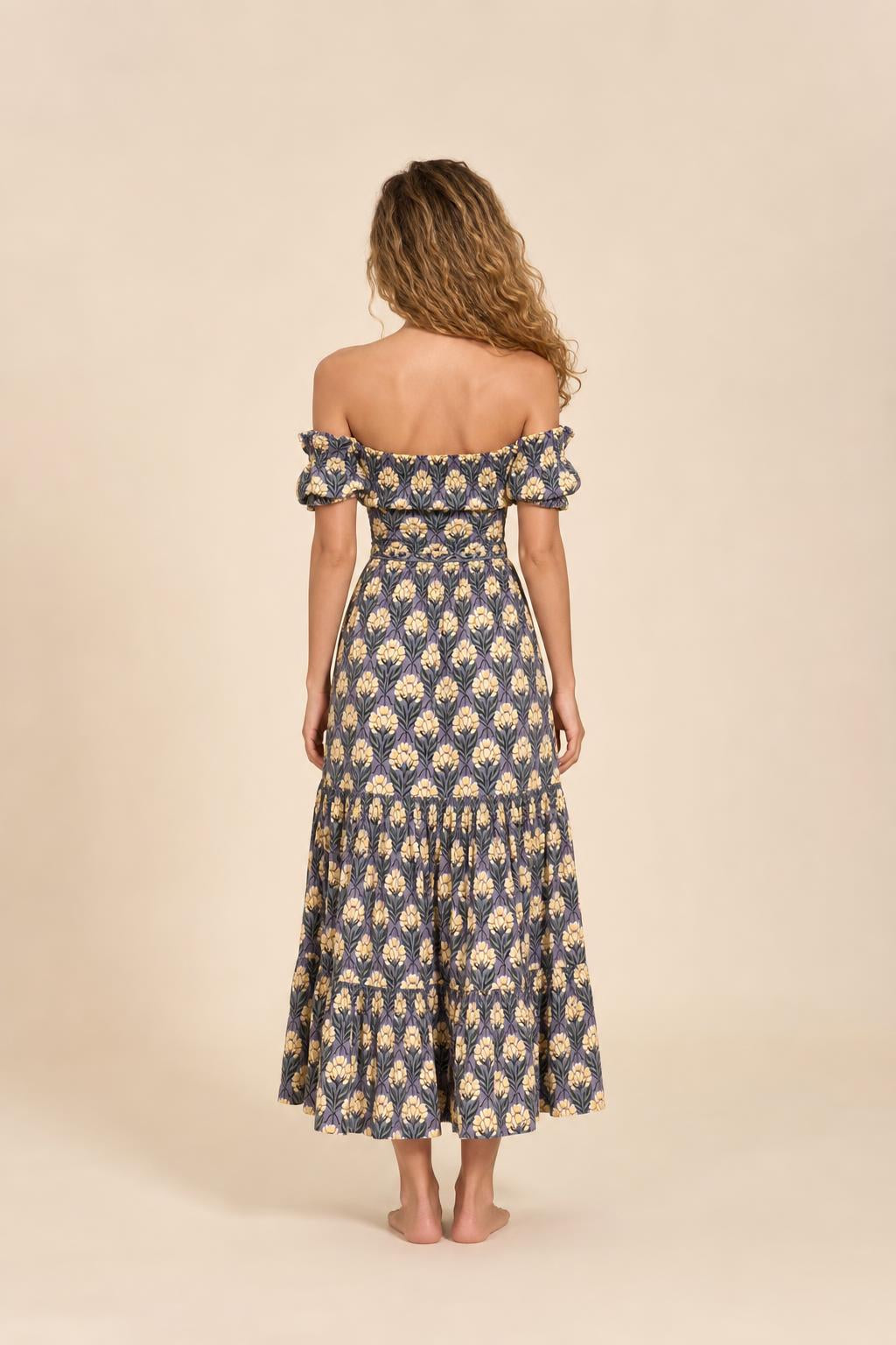 Back view of woman in blue floral midi dress against neutral backdrop