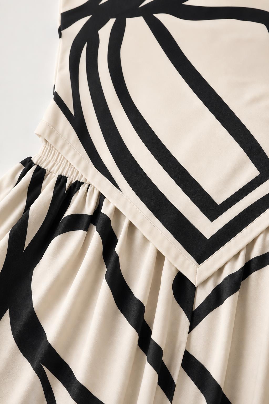 Close-up detail of the folded bodice and elasticated waist on the beige jumpsuit