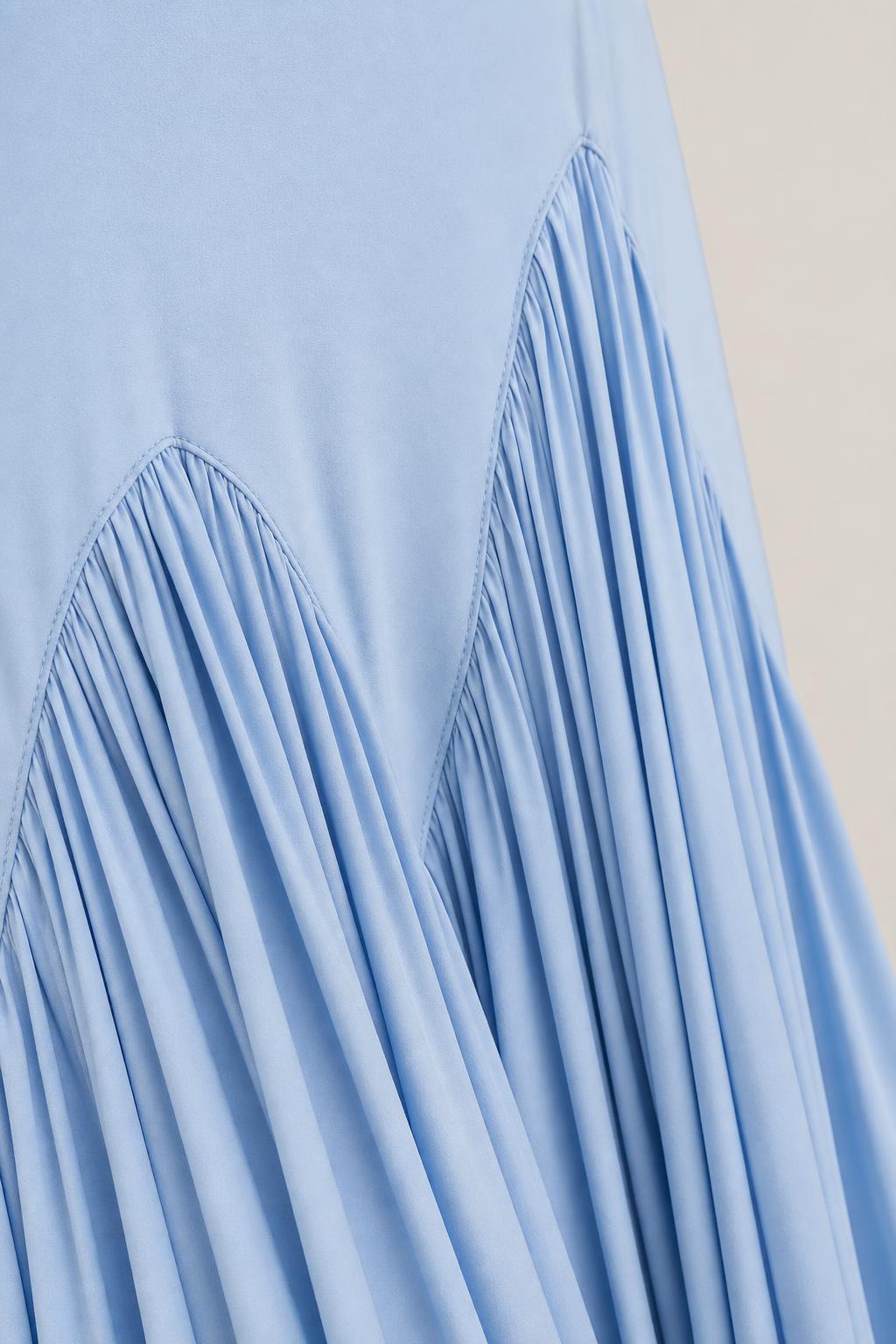 Close-up detail of pleated chevron hem on light blue dress