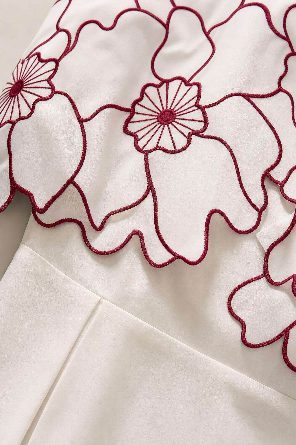 Close-up detail of contrast floral embroidery and scalloped overlay