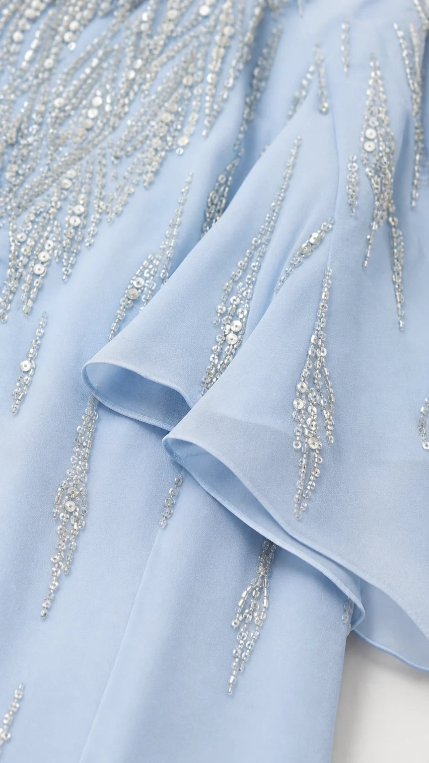 Close-up detail of light blue fabric beadwork and ruffles