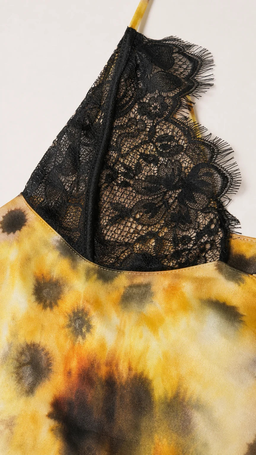 Close-up detail of black floral lace cup on yellow tie-dye fabric