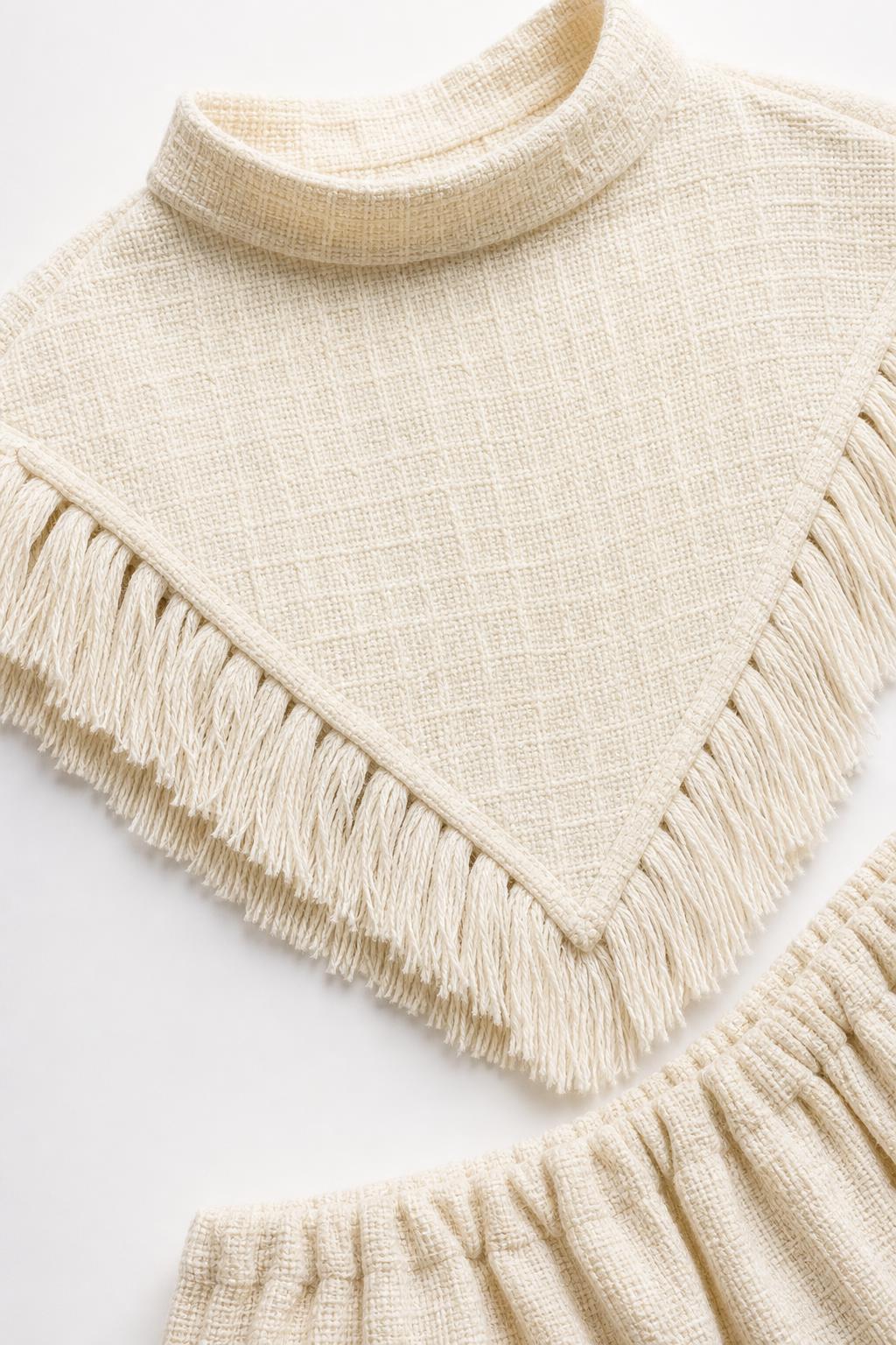 Close-up detail of mock neck and fringe hem