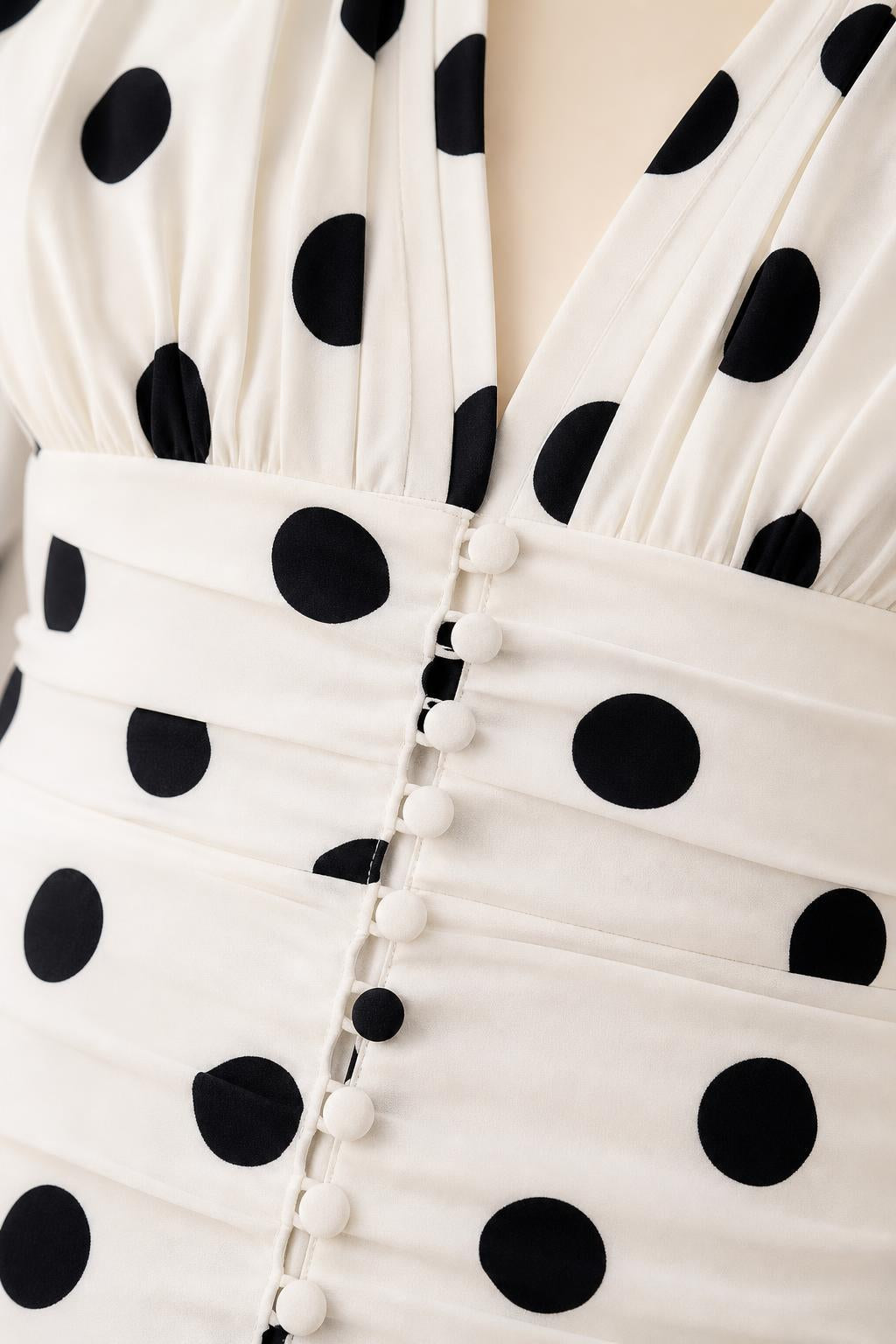 Close-up of ruched front button detail on white polka dot dress