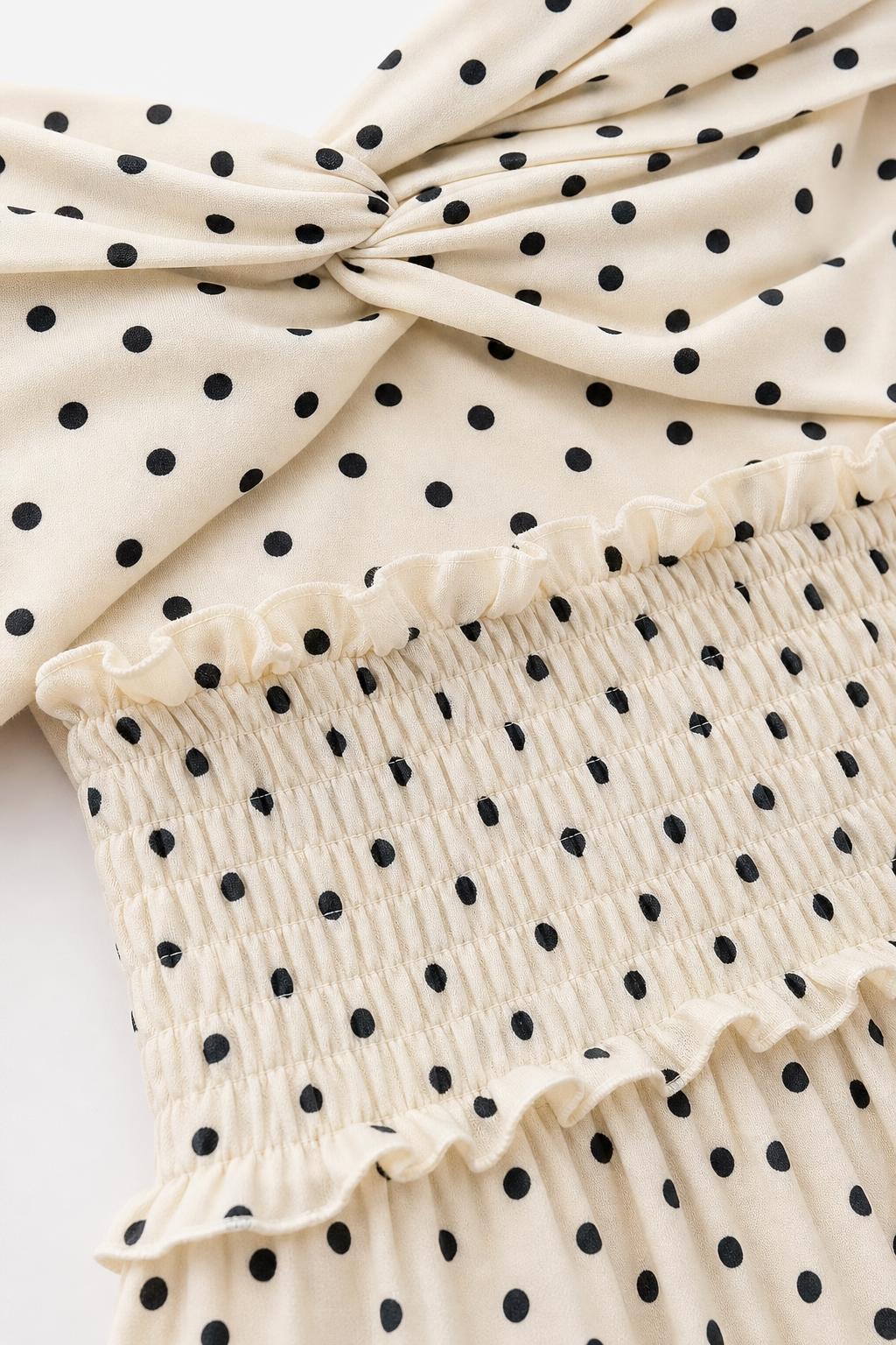 Close-up detail of twist front bodice and smocked waist with polka dot pattern
