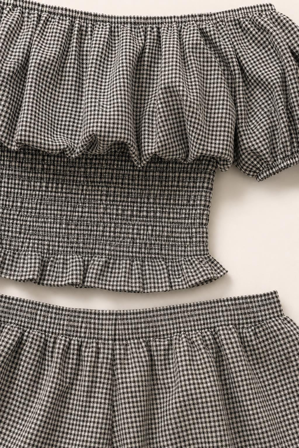 Close-up detail of the black and white gingham fabric, smocked bodice, and ruffle trim