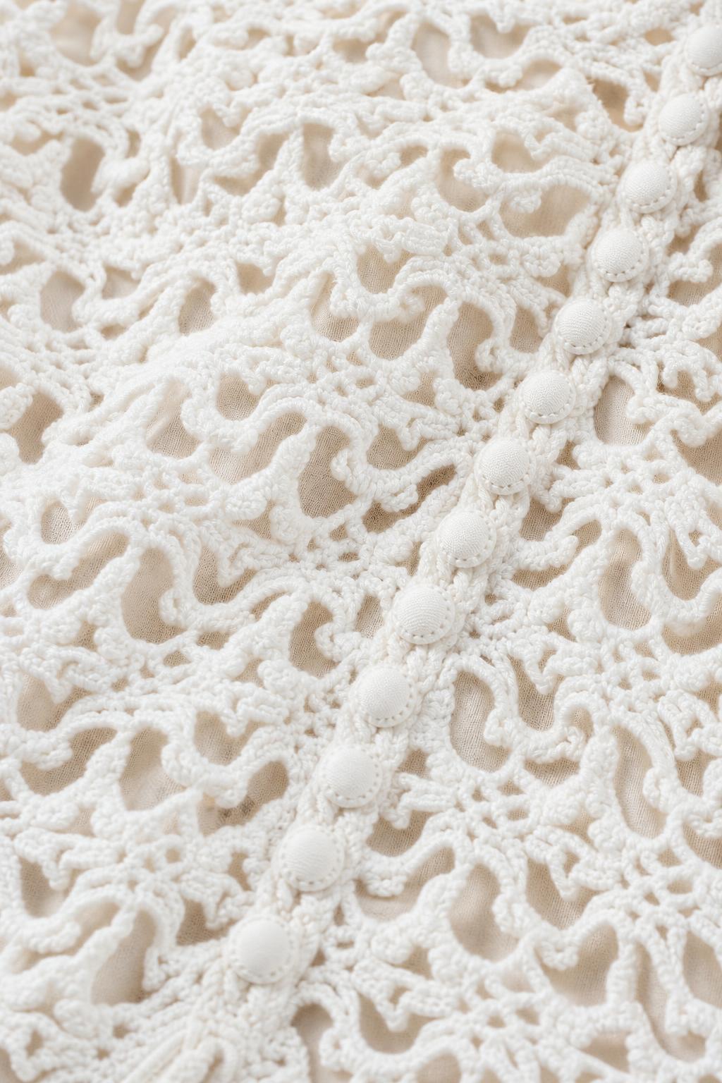 Close-up detail of white crochet lace fabric and buttons