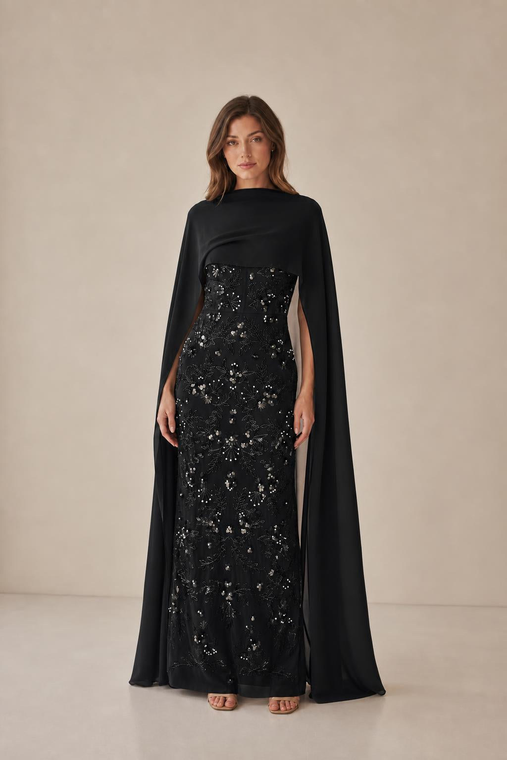 Model wearing black beaded evening gown with cape
