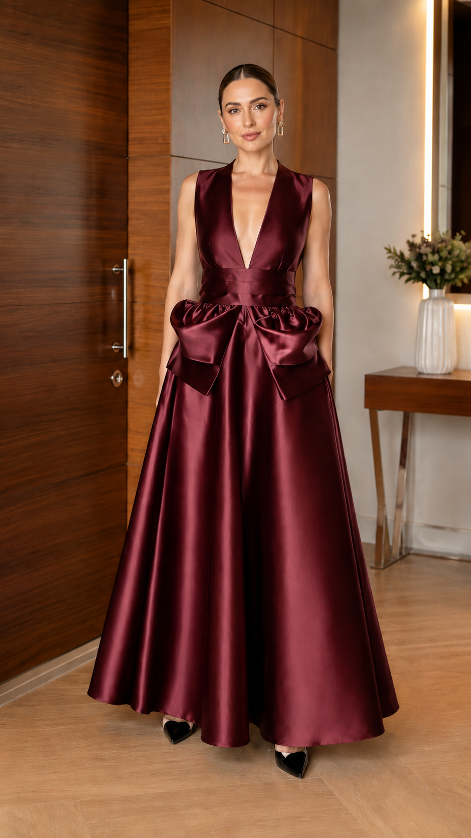 Front view of burgundy sleeveless satin-look evening gown with dramatic waist detail