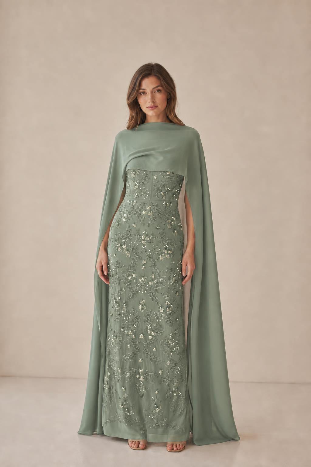 Model wearing sage green formal gown with cape